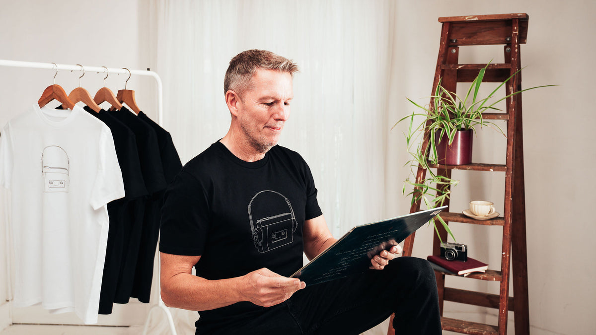 Jason wearing a black Personal Stereo T-shirt while looking at a vinyl record.