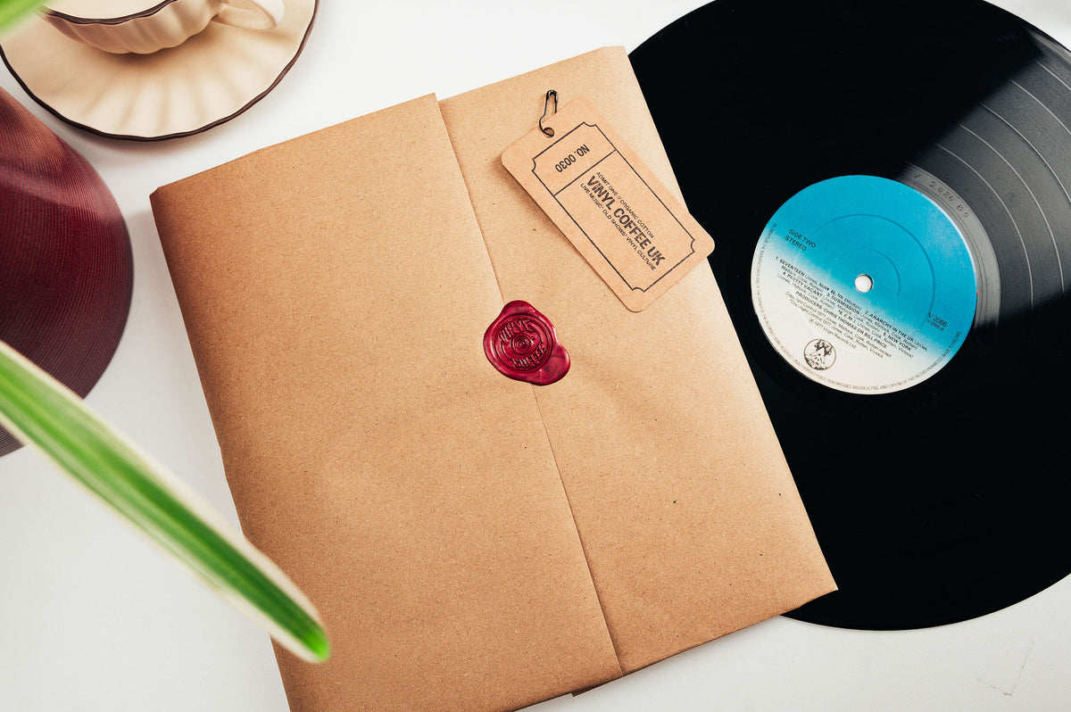 Kraft-wrapped Vinyl Coffee UK parcel with a red wax seal and brand tag beside a vinyl record.